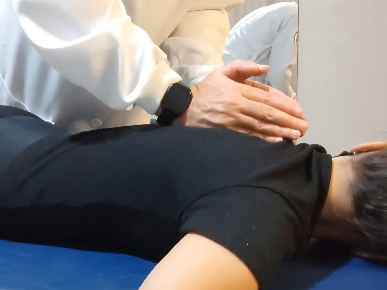 Mãos do Dr. Hualisson Cardoso tratando a região das costas de uma paciente